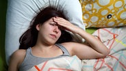 Junge Frau im Bett schaut verzweifelt und legt die Hand gegen die Stirn. © Fotolia.com Foto: Sergey