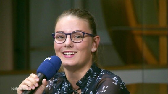 Frida Pauline Huber from the Goethe-Gymnasium in Ludwigslust holds a microphone in her hand.  