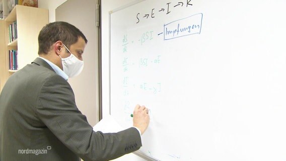 Professor Lars Kaderali vom Institut für Bioinformatik schreibt auf ein Whiteboard. 