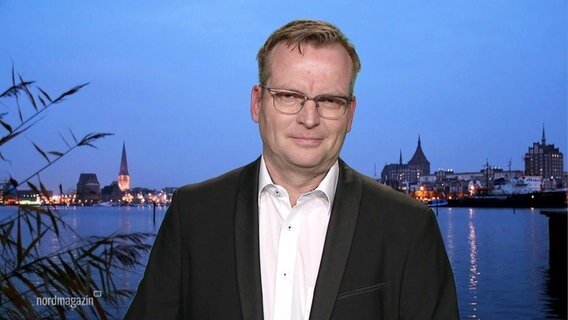 Interview with Andreas Ebel, editor-in-chief of the Ostsee-Zeitung.  Behind him a view of Rostock at night.  