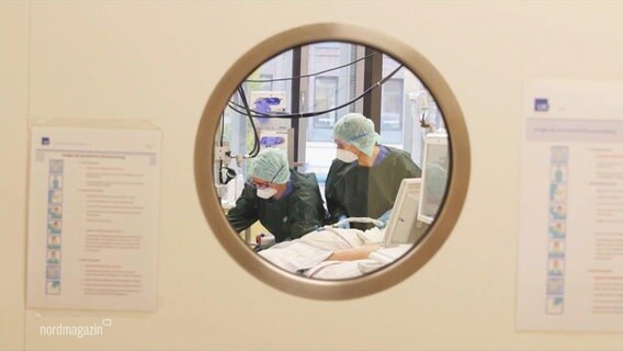 A look through a round window in a door into the operating room.  