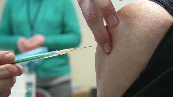 A person is vaccinated against the coronavirus with a syringe on the shoulder.  