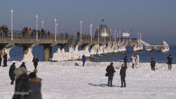 Tourists walk on a stretch of beach.  