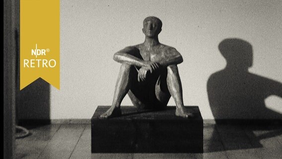 Männliche Skulptur, auf dem Boden sitzend, in einer Ausstellung 1964  