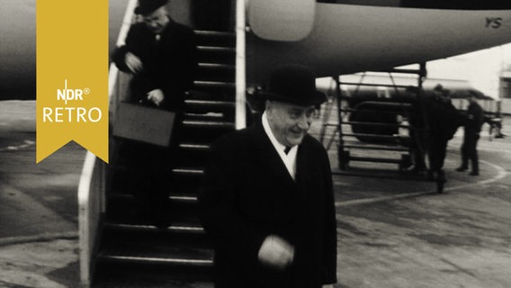 Ministerpräsident Georg Diederichst geht von der Gangway eines Flugzeugs auf das Rollfeld (1964)  
