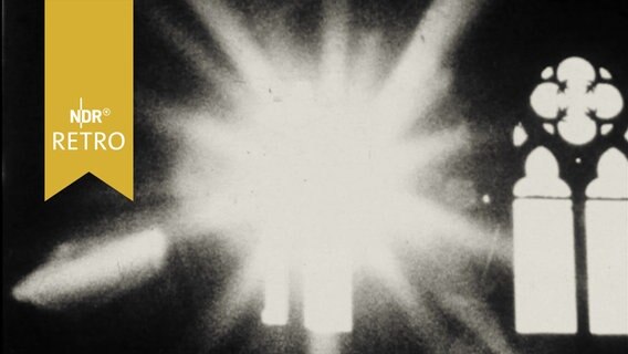 Foto in einer Fotografie-Ausstellung 1964: Ein Kirchenfenster, daneben strahlt ein Blitz oder die Sonne in die Kamera  