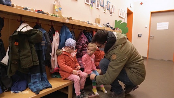 A father crouches in front of his children.  