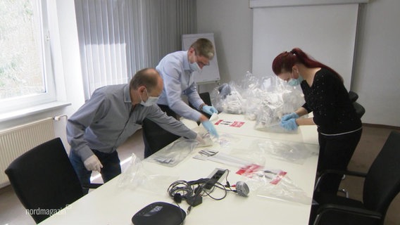 Three people pack corona self-tests for all employees in bags.  