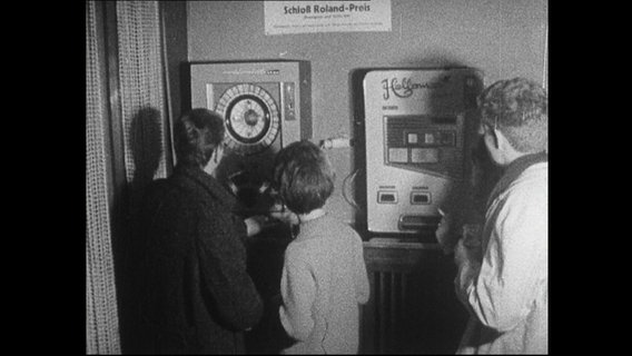 Drei Jugendliche stehen vor Spielautomaten.  
