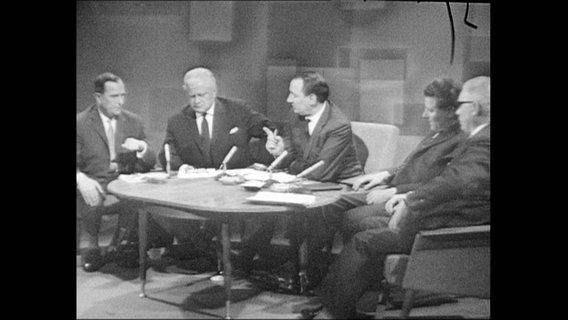 Fünf Männer sitzen an einem Tisch.  