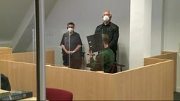 Der Angeklagte verbirgt vor Gericht sein Gesicht hinter einem Aktenordner. 