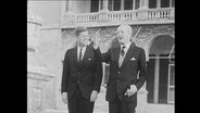 Der US-Präsident John F. Kennedy geht mit Großbritanniens Premierminister Macmillan eine Treppe herunter.  
