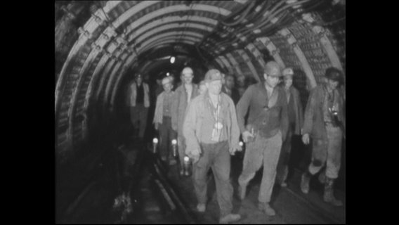 Bergarbeiter laufen durch einen Schacht.  