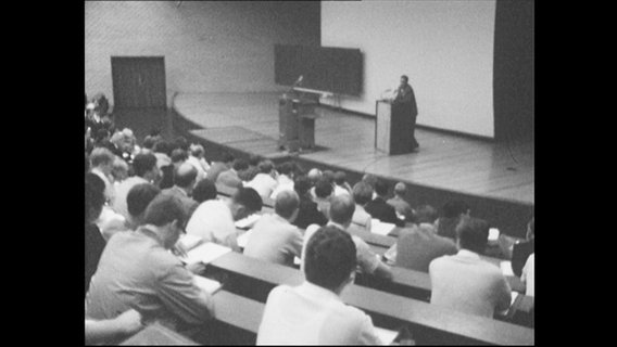 Studenten sitzen während einer Vorlesung in einem Hörsaal.  