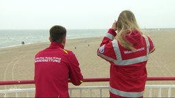 Zwei Personen von der Wasserwacht beobachten den Strand.