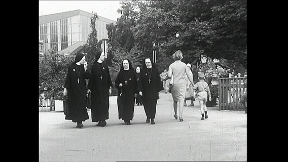 Vier Nonnen laufen einen Weg entlang  