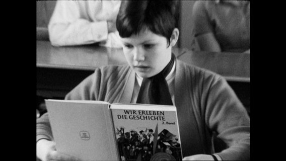 Ein Kind liest in einem Buch mit dem Titel "Wir erleben die Geschichte"  
