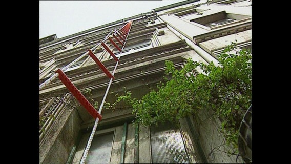 Ein Strickleiter hängt an einer Hausfassade herunter  