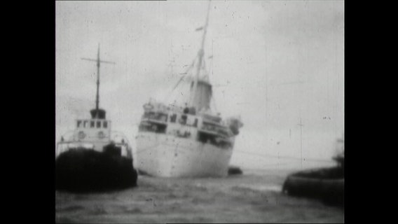 Ein Kreuzfahrtschiff in Schieflage, gezogen von zwei Hochseeschleppern 1964  
