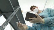 An employee in a test center looks at a test strip.  