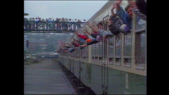 Menschen halten ihre Arme aus den Fenstern eines Zuges und winken (Archivbild).  