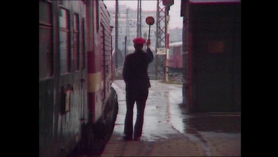 Ein Schaffner am Bahnsteig gibt das Zeichen zur Abfahrt  