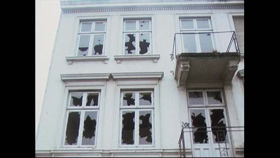 Eine Hausfassade mit zerschlagenen Fensterscheiben.  