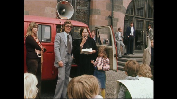 Junge Erwachsene und Kinder demonstrieren mit einem Megafon und Plakaten (Archivbild).  