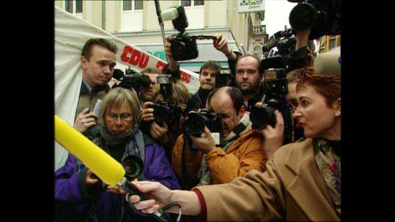 Dutzende Journalisten mit Kameras und Mikrofonen drängen sich  