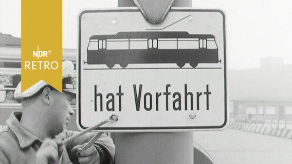 Arbeiter montiert ein Schild "Straßenbahn hat Vorfahrt" in Hamburg 1963  