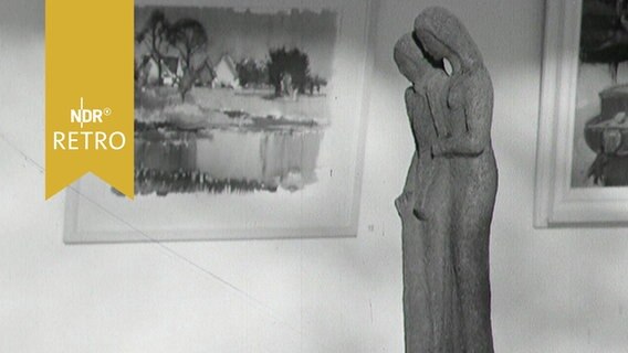Eine Steinskulptur in einer Ausstellung 1963 vor einem Landschaftsgemälde  