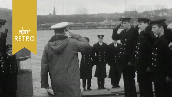 Ein Offizier passiert eine salutierende Reihe Matrosen auf seinem Weg zu einem U-Boot (1964)  