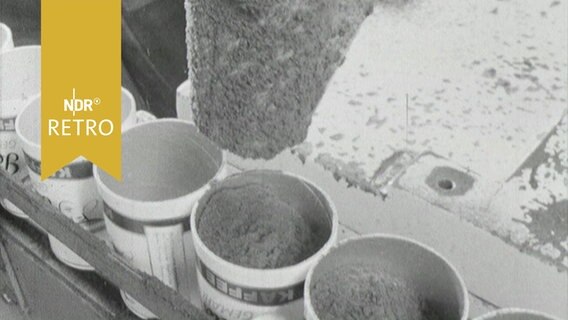 Kaffeeabfüllung (1964): Aus einer Tülle werden nacheinander in einer Reihe stehende Kaffeedosen befüllt  