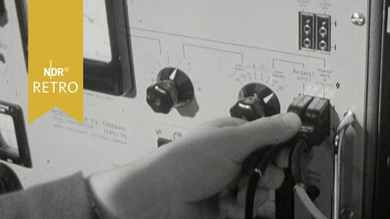 Eine Hand steckt einen Stecker in einer Telefonschaltstelle 1964  