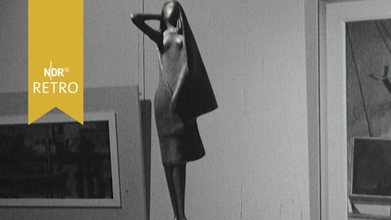 Bronzestatue einer Frauenfigur in einer Ausstellung in Kiel, dahinter Gemälde (1963)  