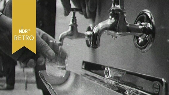 Glas wird an einem Wasserhahn im Wasserwerk Wettmar mit Leitungswasser gefüllt (1963)  