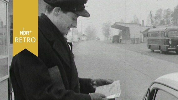 Grenzer kontrolliert Papiere an einem Autofenster 1963  