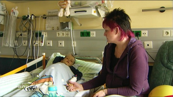 Eine Mutter sitzt am Krankenbett ihres Kindes  