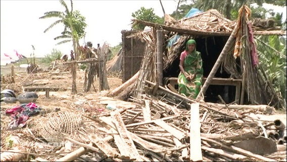 Eine Frau sitzt in den Trümmern eines Hauses in Bangladesch  