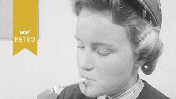 Stewardess in Pause zündet sich eine Zigarette an (1958)  