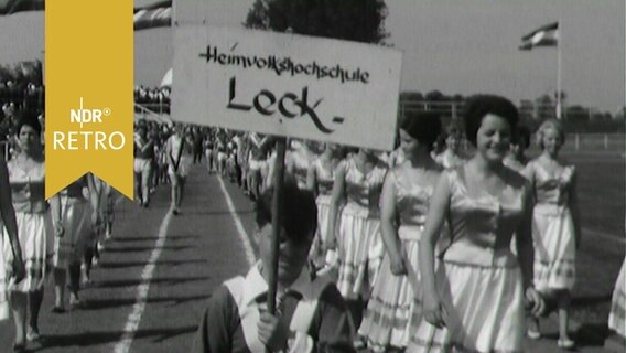 Nutzer der "Heimvolkshochschule Leck" mit Schild beim Einzug zur Einweihung des neuen Sportstadions in Leck/ Schleswig-Holstein (1963)  