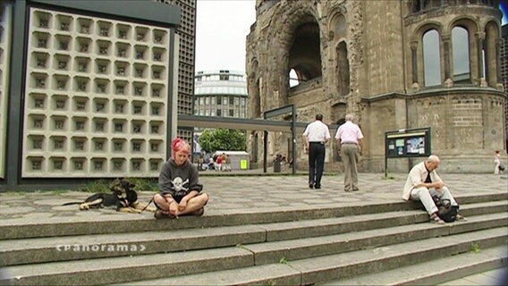 Eine junge Frau sitzt mit ihrem Hund auf einer Treppe  