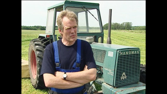 Ein Bauer steht vor einem Traktor  