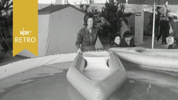 Frau präsentiert ein Faltboot auf einer Campingausstellung in Hamburg 1964  