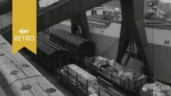 Umschlagbahnhof am Kai in Bremen 1964 mit Güterzügen neben der Bordwand eines Frachtschiffs  