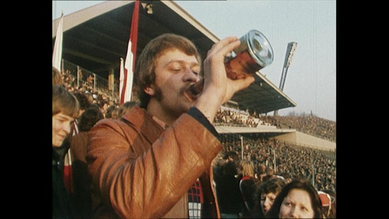 Ein Jugendlicher trinkt Alkohol im Stadion  
