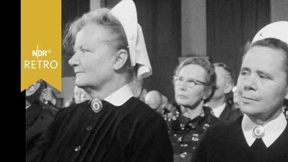 Zwei Krankenschwestern mit Häubchen und Ordenstracht im Publikum einer Festveranstaltung (1964)  