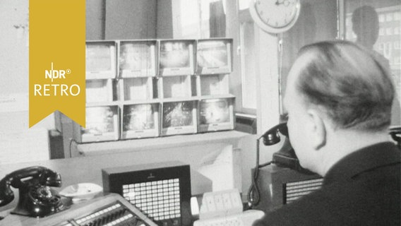 Polizeibeamter im Büro an der Schreibmaschine vor einer Bildschirmwand der "Fernaugen-Bildschirme" (1964)  