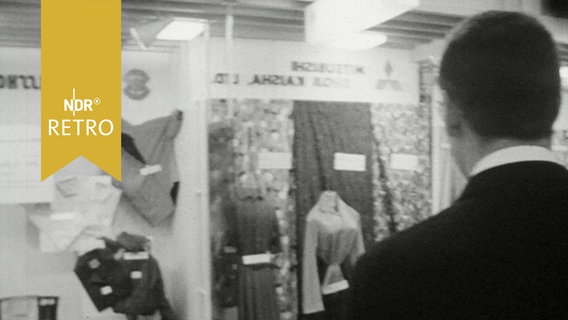 Mann vor Vitrinen mit hochpreisigen Kleidungsstücken (1964)  