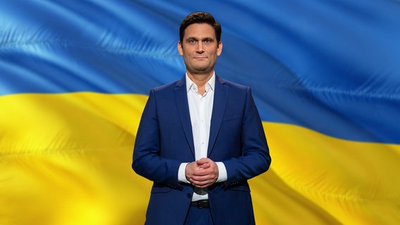 Christian Ehring vor einer ukrainischen Flagge.  